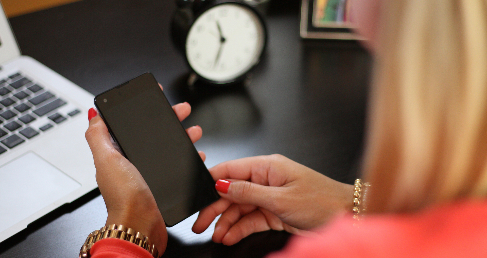 Whats-happening-to-our-attention close up of woman at desk with phone in her hand
